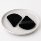 Two black silicone coasters on a white plate with a white background